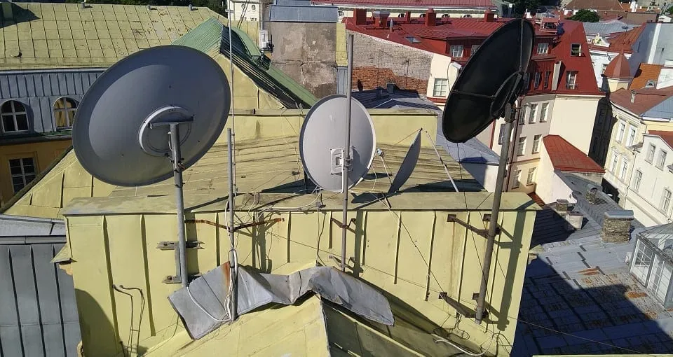 Vanad satelliitantennid mastide ja tõmmitsatega Pärnu mnt 10 plekk-katusel, taustal Tallinna vanalinna katused