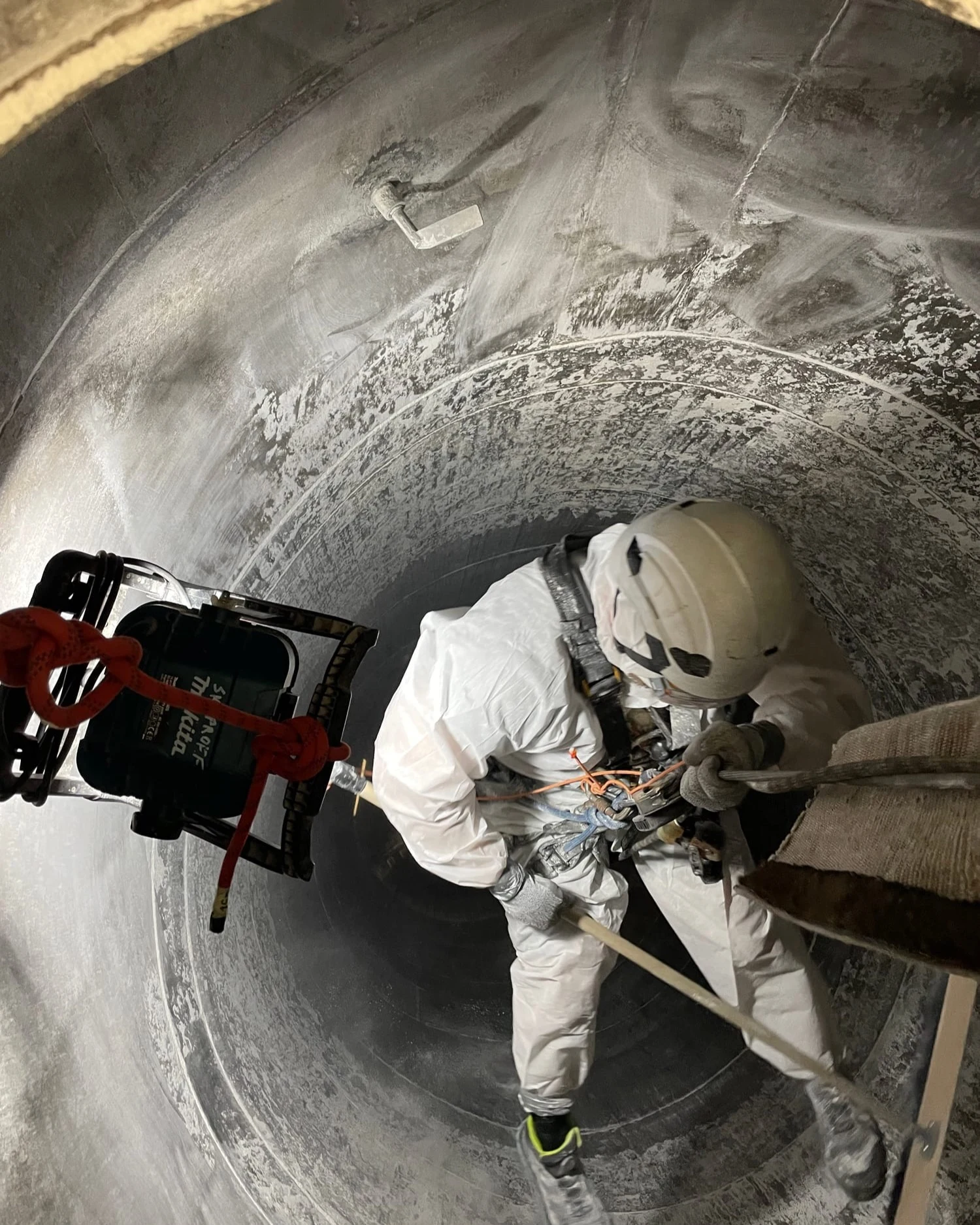 Skyproffi tehnik köisligipääsul kaitseülikonnas tolmust silo seina puhastamas