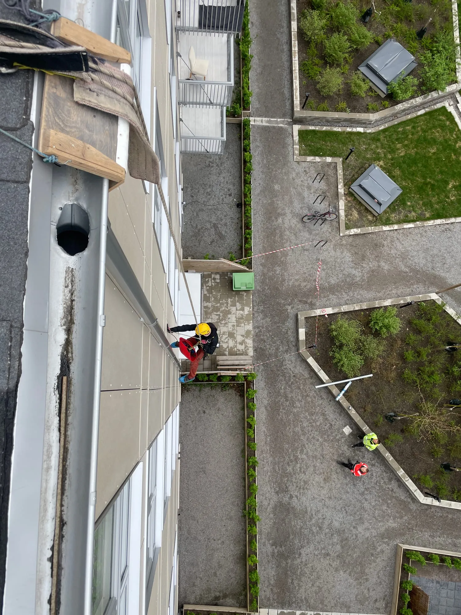 Skyproffi tehnik laskub üle katuseääre Stockholmi hoone fassaadile, all kolleeg abistamas